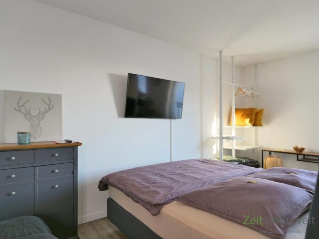 Doppelbett und TV hinter dem Raumteiler
